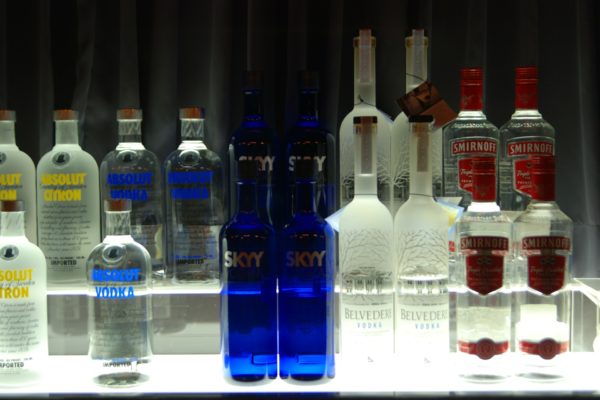 Mehre Vodkaflaschen stehen nebeneinander auf einem beleuchteten Glasregal
