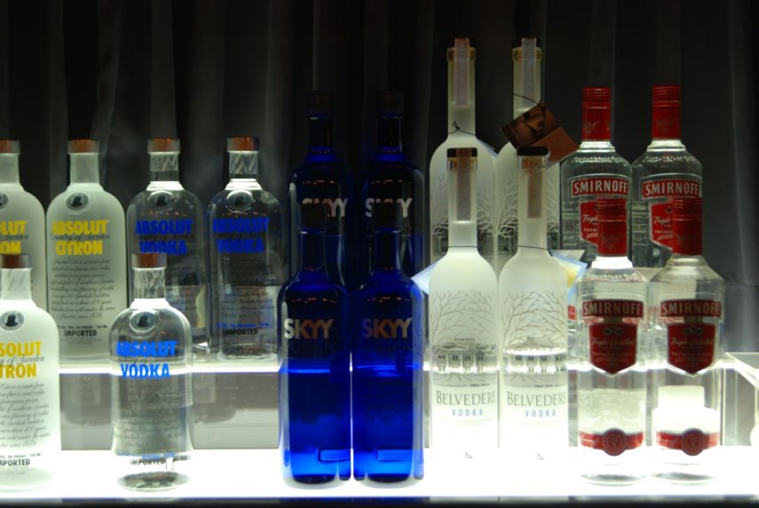 Mehre Vodkaflaschen stehen nebeneinander auf einem beleuchteten Glasregal